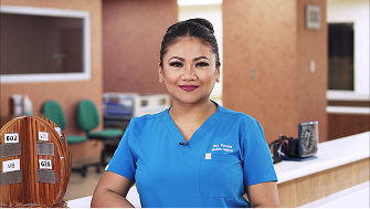Woman in blue scrubs by a desk.