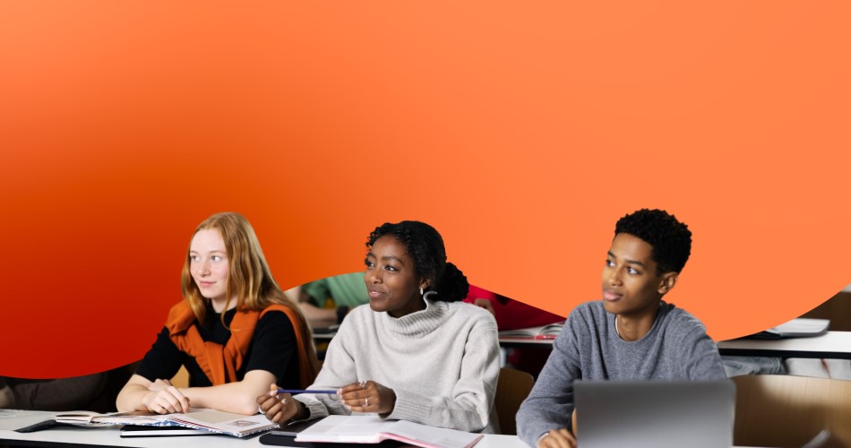 Students learning at desks in orange classroom.